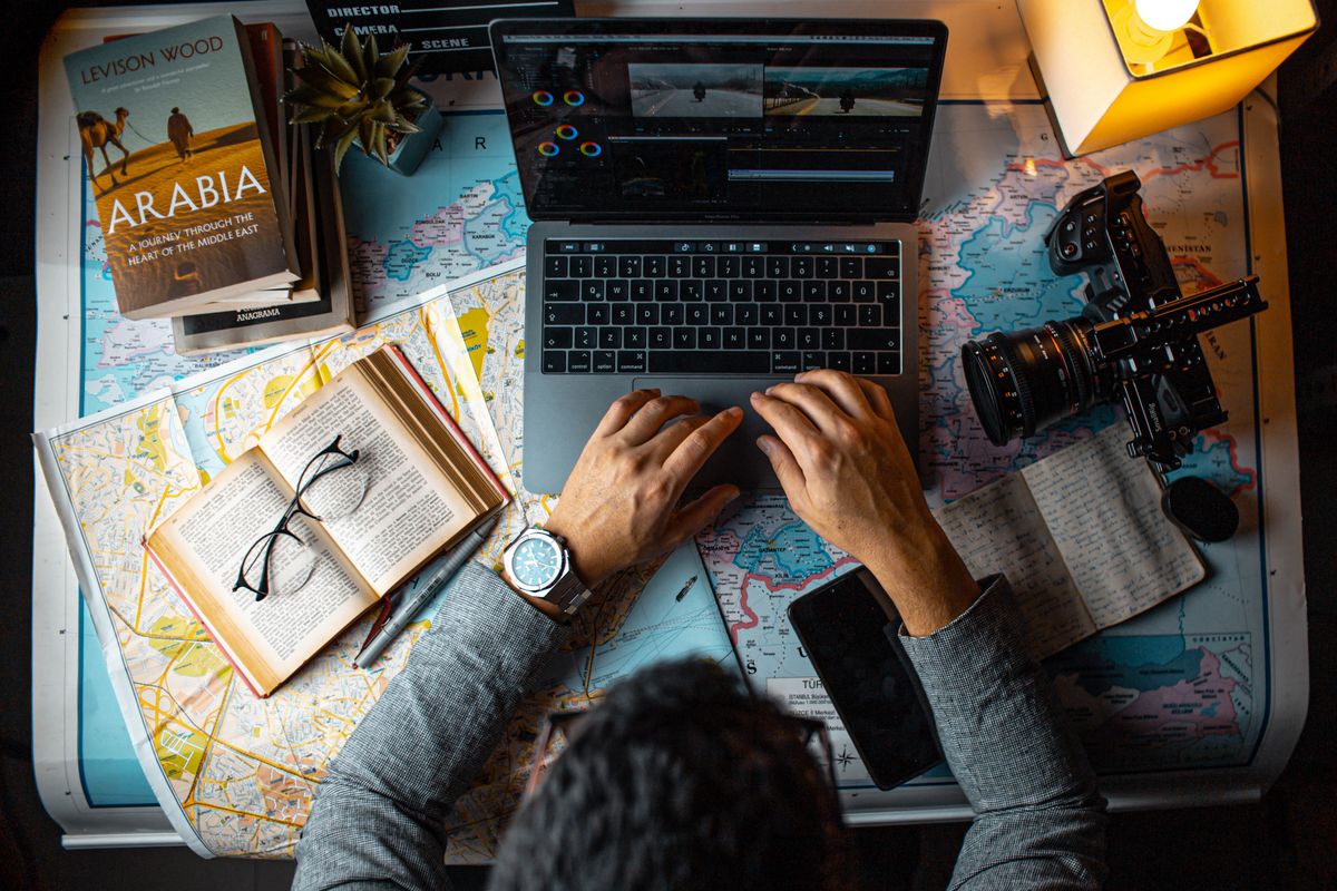 Travel planner working with maps and a laptop